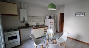 una cocina con electrodomésticos blancos, mesa y sillas en DEPARTAMENTO AGOTE en Mendoza