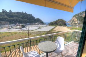 balcón con mesa, sillas y vistas al océano en Astacos Studios en Paleokastritsa