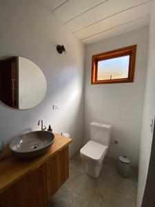 a bathroom with a sink and a toilet and a mirror at Chalé Jacarandá - Hidro - Wifi e mais in Sapucaí-Mirim