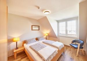 ein Schlafzimmer mit einem Bett und einem blauen Stuhl in der Unterkunft Ferienwohnung mit Seesicht Grimmershörnbucht in Cuxhaven