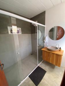 a bathroom with a shower with a sink and a mirror at Chalé Jacarandá - Hidro - Wifi e mais in Sapucaí-Mirim