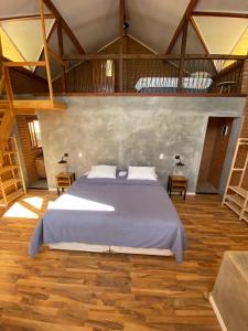 a bedroom with a large bed and wooden floors at Chalé Jacarandá - Hidro - Wifi e mais in Sapucaí-Mirim