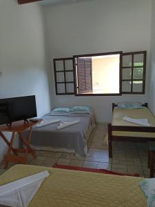 a room with two beds and a table and a window at Pousada Vento Norte in Ilhabela