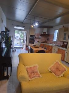 a living room with a yellow couch and a kitchen at Villa mendola in Cianciana