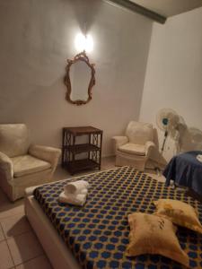 a bedroom with a bed and two chairs and a mirror at Villa mendola in Cianciana