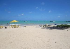 a beach with a yellow umbrella and the ocean at Maragogi Beach Flats in Maragogi