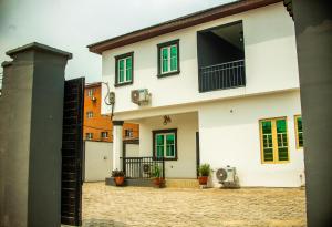 ein weißes Haus mit grünen Fenstern und einem Innenhof in der Unterkunft Mansal Luxury Apartments in Lagos