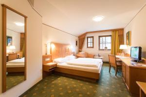 a hotel room with a bed and a desk and a mirror at Alpenrast Tyrol in Mils bei Imst