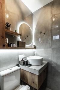 ein Badezimmer mit einem Waschbecken, einem WC und einem Spiegel in der Unterkunft Cinnamon in Volos
