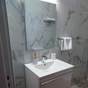 a white bathroom with a sink and a mirror at Artemis House in Limassol