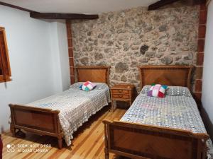2 camas en una habitación con una pared de piedra en El Quebrantahuesos, en Peralejos de las Truchas