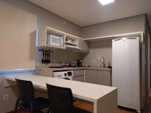 cocina con mesa, sillas y nevera en Villa Leopoldina - Studios de aluguel por temporada no Moinhos de Vento, en Porto Alegre