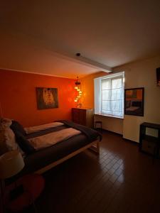 a bedroom with an orange wall with a bed and a window at Charming Room in the heart of Locarno in Locarno
