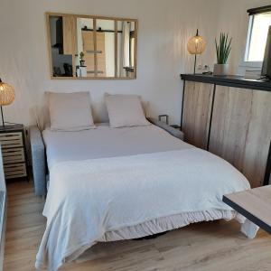 - une chambre avec un grand lit blanc et un miroir dans l'établissement Studio climatisé cosy avec grande piscine chauffée, au Cap d'Agde