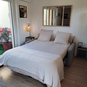 duże białe łóżko w sypialni z lustrem w obiekcie Studio climatisé cosy avec grande piscine chauffée w Cap d'Agde