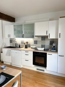 a kitchen with white cabinets and a black oven at Le Rabelais, superbe appartement en duplex, proche forteresse et monument historique in Chinon