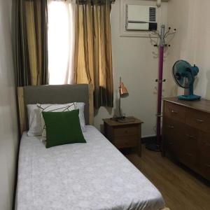 um quarto com uma cama com uma almofada verde e uma janela em The Redwoods Fairview Quezon City em Manila