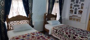 two beds in a room with curtains and windows at Barlos XVIII in Bukhara