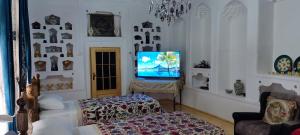 a living room with a tv and a bed at Barlos XVIII in Bukhara