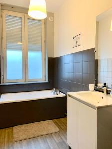 a bathroom with a bath tub and a sink at Van Gold - Appartement - Centre Ville in Calais