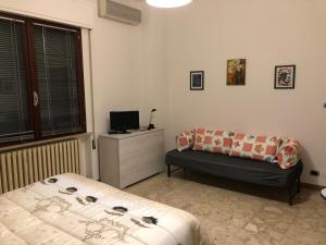 a bedroom with two beds and a dresser and a television at SMM Apartment in Ferrara