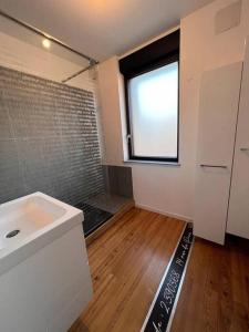 La salle de bains est pourvue d'un lavabo blanc et d'une fenêtre. dans l'établissement Villa du parc au cœur de Malo, à Dunkerque