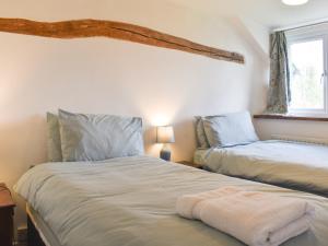 2 Einzelbetten in einem Zimmer mit Fenster in der Unterkunft Keepers Cottage in Garway