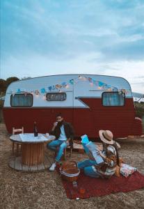un par de personas sentadas frente a una caravana en SA MOLA GLAMPING EXPERIENCE Roulotte, en Escolca