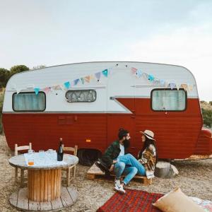 two people sitting in front of a trailer at SA MOLA GLAMPING EXPERIENCE Roulotte in Escolca