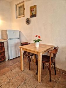 a kitchen with a wooden table with chairs and a refrigerator at House among olive trees with a sea view 3 in Ankaran