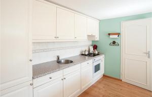 una cocina con armarios blancos y fregadero en Oud Kempen Bungalow 41, en Stavenisse