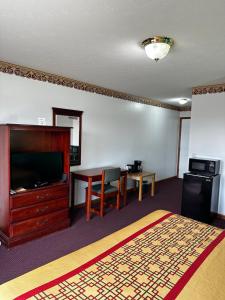 a hotel room with a bed and a desk and a television at Attica Inn in Attica