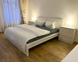 um quarto com uma cama com lençóis brancos e almofadas em 666 Plagwitz Apartment Kulturviertel em Leipzig