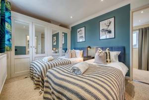 two beds in a room with blue walls at Pheasant House by Apricity Property - 5 bedrooms, 2 Bathrooms and a WC, Foosball table, free parking, Garden, Workspace in Cirencester