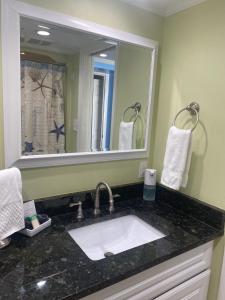 a bathroom with a sink and a large mirror at Ocean Front 53 Steps in Myrtle Beach