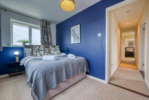 a blue bedroom with a bed with a blue wall at Pheasant House by Apricity Property - 5 bedrooms, 2 Bathrooms and a WC, Foosball table, free parking, Garden, Workspace in Cirencester