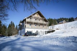 a large house with a car parked in the snow at Krušnohorské Stráně in Loučná pod Klínovcem