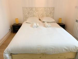 duże białe łóżko z dwoma ręcznikami w obiekcie Le Cocon de Saint Arnoult w mieście Saint-Arnoult-en-Yvelines