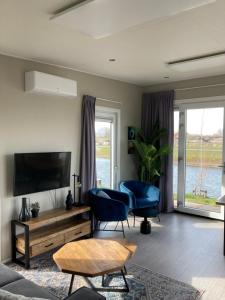 un soggiorno con 2 sedie blu e una TV di Tiny vakantiehuis aan het water met eigen steiger en airco a Kampen