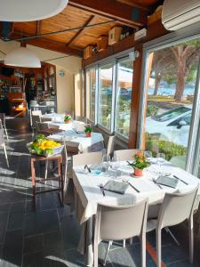 un restaurante con mesas y sillas blancas y ventanas en Locanda La Lucciola, en Portovenere