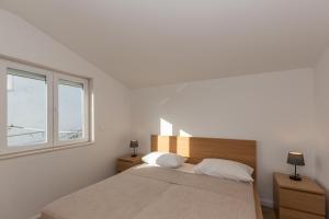 a white bedroom with a bed and a window at Apartments Ana in Biograd na Moru