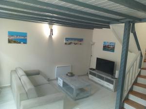 ein Wohnzimmer mit einem Sofa und einem TV in der Unterkunft Maison Normande avec patio in Le Havre