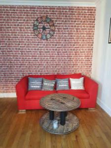 un sofá rojo con una mesa frente a una pared de ladrillo en Paris Esprit loft, lumineux en Aubervilliers