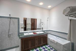 ein Badezimmer mit einer Badewanne, einem Waschbecken und einem Spiegel in der Unterkunft Riad Dari Fes in Fès