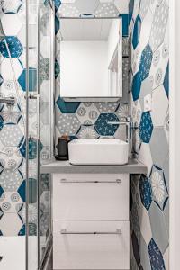 y baño con azulejos azules y blancos y lavabo. en Résidence Bonaparte en Laval
