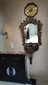 a mirror on a wall with a dresser and a clock at Appartement Fes très propre et calme in Fez