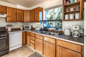 a kitchen with wooden cabinets and a sink at THE ROGUE WAVE-Beach Access, Ocean Views, Private in Kodiak