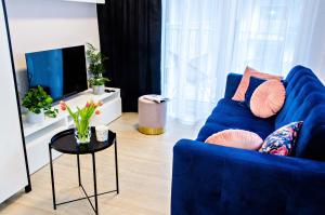 un salon avec un canapé bleu et une télévision dans l'établissement Cherub Apartment, à Wrocław