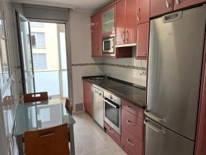 una cucina con armadi rossi e frigorifero in acciaio inossidabile di Exclusivo Apartamento Con Parking a Torrelavega