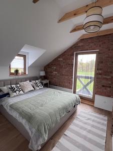 sypialnia z dużym łóżkiem i ceglaną ścianą w obiekcie Domek pod lasem „2” w mieście Pasłęk